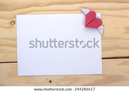 origami heart with wings over white paper sheet for love letter.