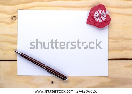 origami heart and pen on white paper sheet for love letter.