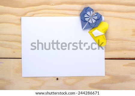 love letter with origami blue and yellow heart on wooden table
