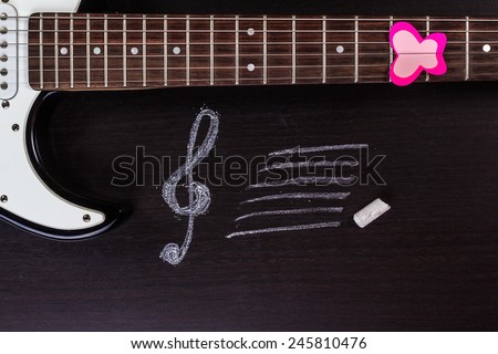 Electric guitar with treble clef on dark background