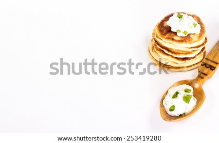 isolated russian food - stack of pancake and wooden spoon with sour cream and herbs