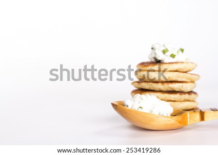 isolated slavic food - stack of pancake and wooden spoon with sour cream and herbs