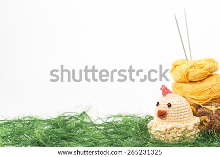 knitting toy chicken on a background of thread grass