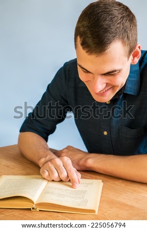 handsome young man reading a book at his desk, on blue background