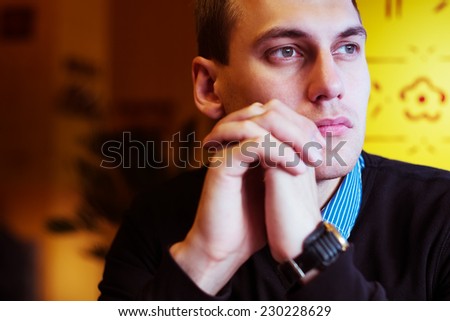 young attractive man looking and thinking. portrait of handsome man sitting in cafe