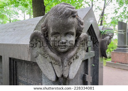 Angel in the old cemetery. Angel with wings on an old crypt. A sculpture of an angel - the infant\'s head with wings. The decoration of the tomb at the Tikhvin cemetery, St. Petersburg.