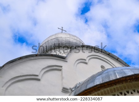 Church dome with a cross. The Christian white Church bottom view. The cross on the Church. A small Church on the background of blue sky.