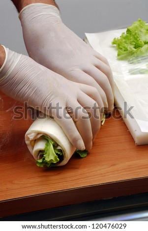Hand preparing rolled sandwich wrap.