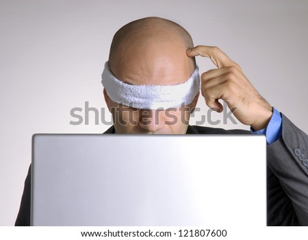 Confused blindfolded bald head man using a computer.