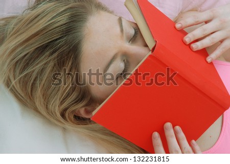 Young blonde woman reading and kissing a red book,lying down.