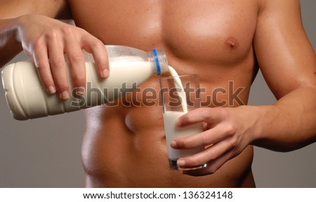 Shaped and healthy body man pouring milk glass.