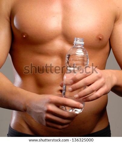 Shaped and healthy body man holding mineral water bottle.