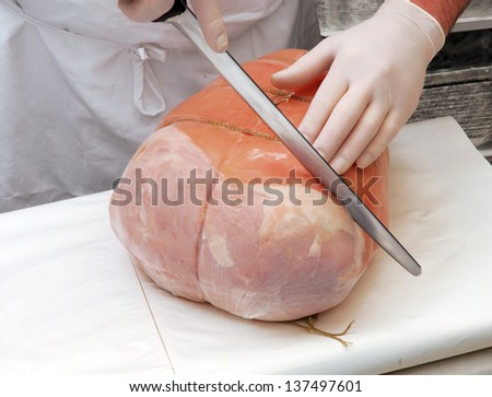 Butcher meat slicing prosciutto ham in a warehouse.