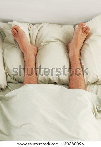 Funny feet over a cushion in bed.Barefoot on bed.
