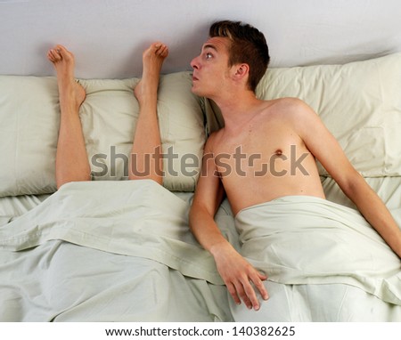 Disgust young man smelling woman feet.Funny couple lying down on bed.