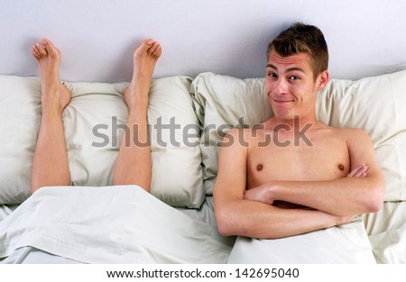Funny young couple on bed,young man lying down on bed behind wife foot.