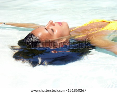 Young woman relaxed and floating on water.Taking sun.