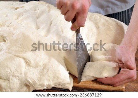 Cook preparing and cutting bread flour for pizza and bread