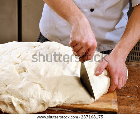 Cook preparing and cutting bread flour for pizza and bread