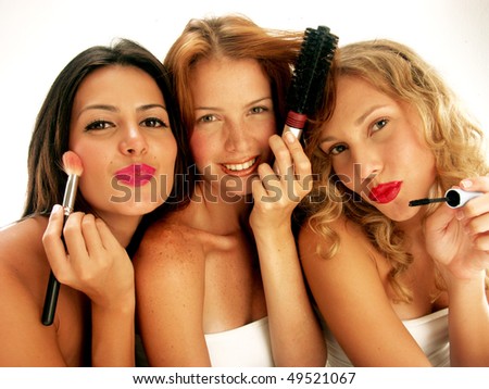 Three young women applying makeup mirror.