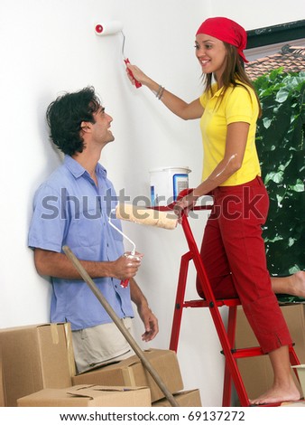 Hispanic couple painting a new house,