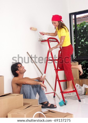 Hispanic couple painting a new house,