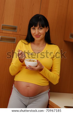 Young pregnant woman eating cereal. Pregnant woman holding a cereal bowl.