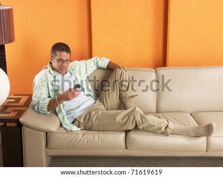 Relaxed young man lying down on sofa with a mobil phone.