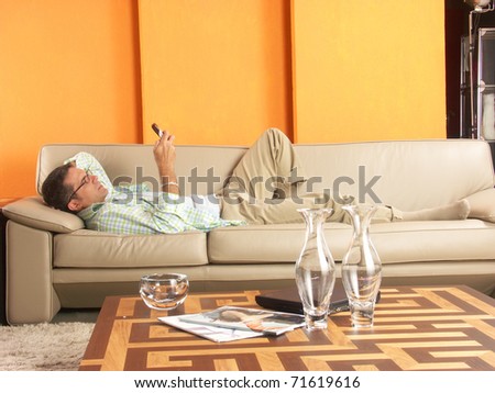 Relaxed young man lying down on sofa with a mobil phone.