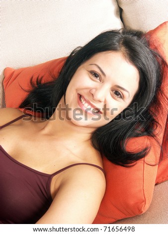 Happy hispanic woman on a sofa. Young woman on a couch.,