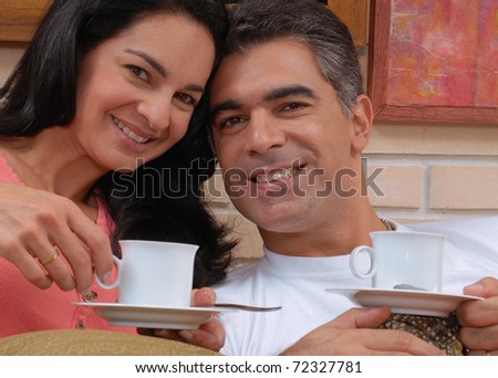Mid adult couple drinking coffee in a living room.