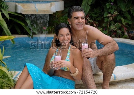 Latin couple drinking strawberry milkshake in a swimming pool.
