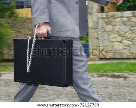 businessman walking with a secure briefcase.   Businessman holding a handcuffs suitcase.