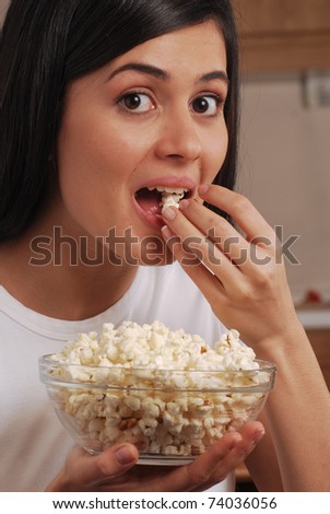 Young woman eating pop corn. Young woman holding a pop corn bowl.