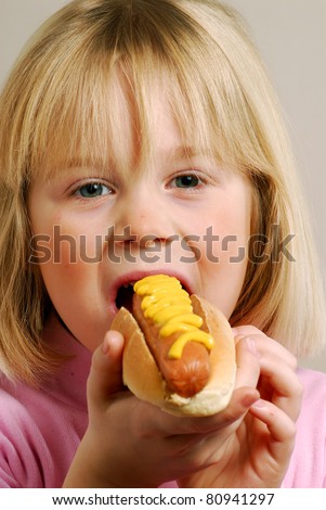 stock photo Little girl eating a hot dogKid eating hot dog