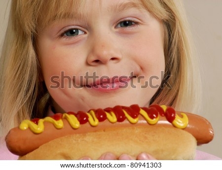 stock photo Little girl eating a hot dogKid eating hot dog