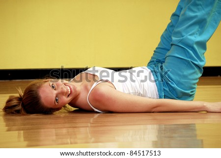 Young blonde woman in a gym. Young woman stretching in a gym.