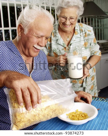 Grandparents eating cereal corn flakes at kitchen.