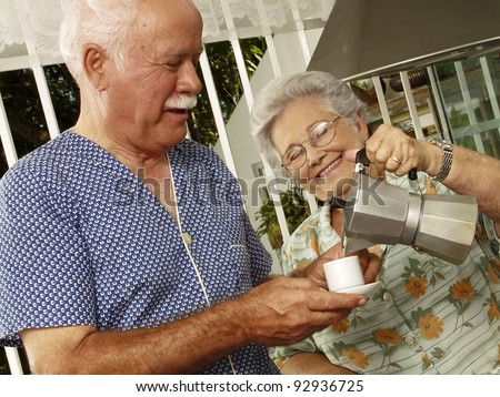 Happy grandparents couple drinking coffee in the kitchen.
