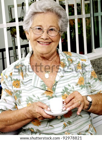 Grand mother drinking coffee in a kitchen.