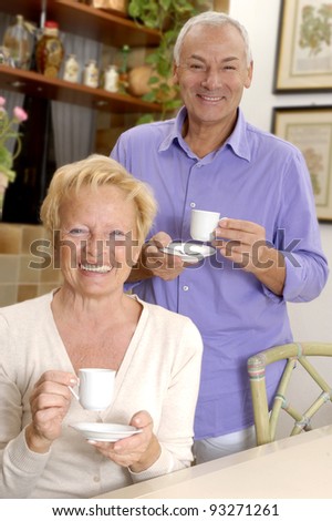 Happy senior couple drinking coffee at kitchen.