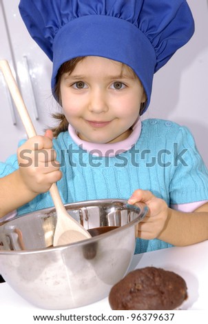 Little girl cooking chocolate in a kitchen.Little girl using a chef cap and cooking in a kitchen.