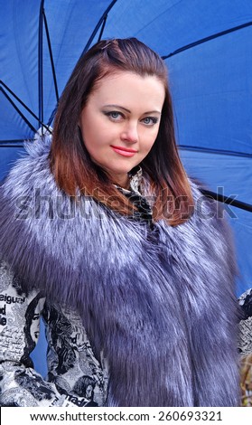 Fashion style young woman holding a big blue umbrella.