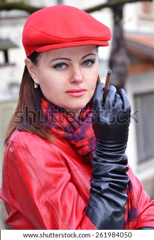 Fashion style woman smoking wearing red hat,black gloves and red leather jacket.