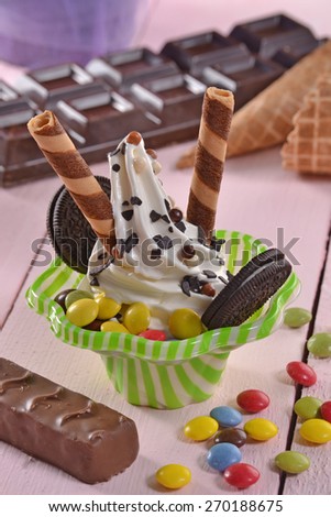 Vanilla ice cream sundae and chocolate cookies on party background.