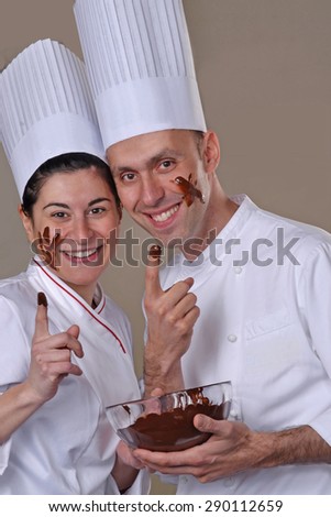 Funny young cook couple tasting chocolate cream.