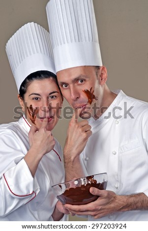 Funny young cook couple tasting chocolate cream.