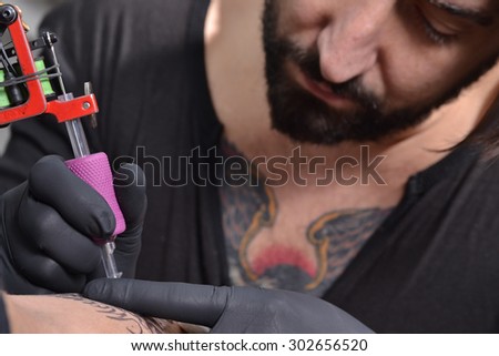Tattoo artist working tattooing an arm.