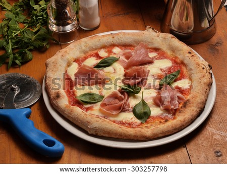 Pizza dish and ingredients on wood table.