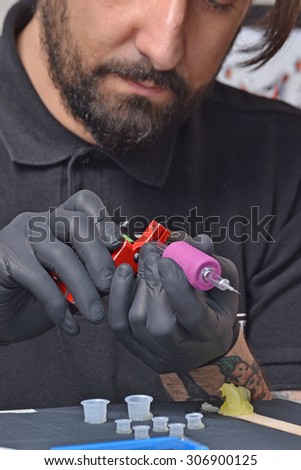 Tattoo artist preparing his ink machine gun before get start working.